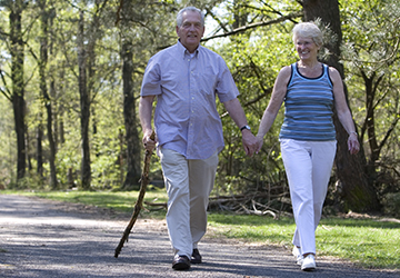 um casal de idosos caminha em um parque