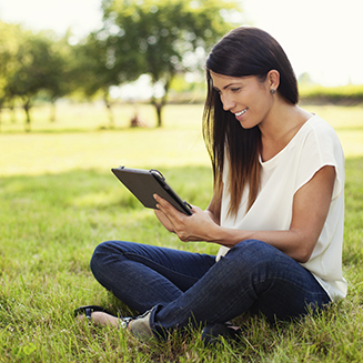 Mulher sorrindo segurando um tablet ao ar livre