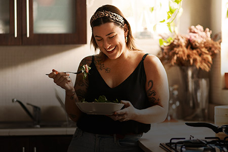 Imagem de uma mulher sorridente com um pote de refeição na mão