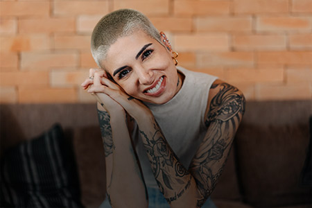 Ao fundo imagem de uma mulher tatuada sorrindo