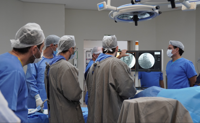 Cirurgiões em sala de cirurgia olhando para a tela de monitoramento